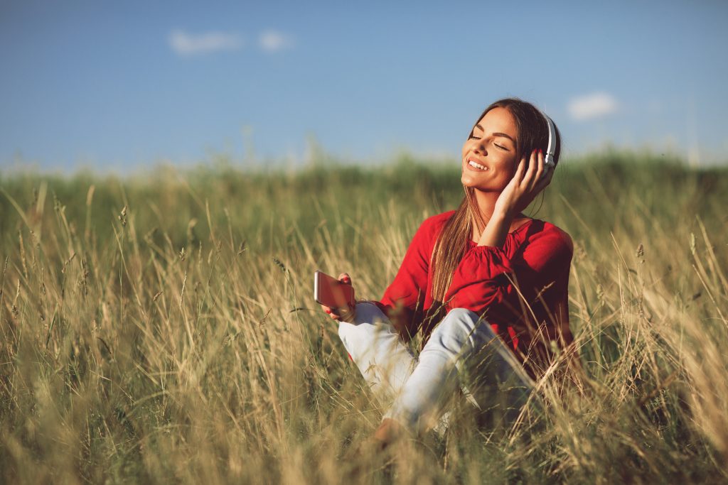 Young woman listens to music via headphones and smartphone outdoor