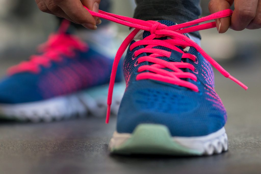 Running shoes - woman tying shoe laces. Closeup of fitness woman getting ready for engage in the gym